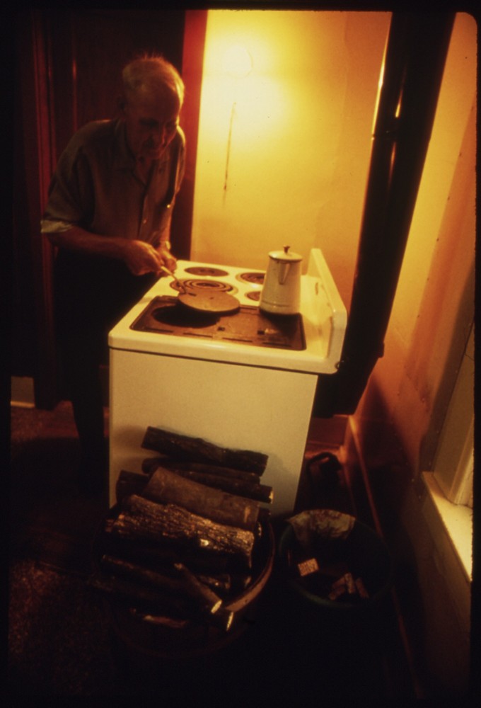 Person cooking on a wood-burning stove in a home kitchen